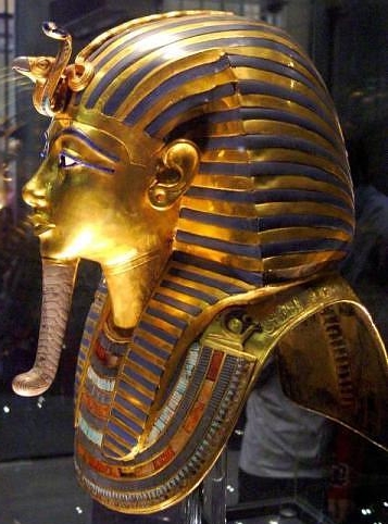 15e - Barbe postiche : Ici la barbe recourbe de Toutankhamon; symble de royaut, la barbe des Pharaons vivants est en forme de trapze et droite alors que celle des dieux est recourbe  son extrmit. Quand le pharaon est reprsent dans le monde des morts (sur le masque funraire par exemple), il s'identifie alors  Osiris et porte la barbe recourbe des dieux.